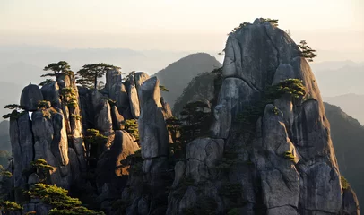Crédence de cuisine en verre imprimé Monts Huang Huangshan Mountain in Anhui Province, China. View at sunrise from Dawn Pavilion viewpoint with a rocky outcrop and pine trees. Scenic view of peaks and trees with shadows on Huangshan Mountain, China.