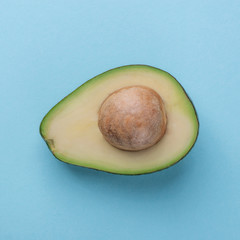 Avocado half with kernel on blue background