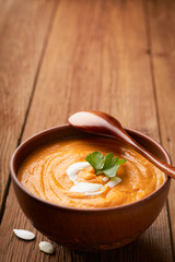 Vertical frame brown bowl of pumpkin soup on a wooden background with copy space