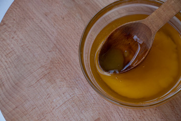 Sweet yellow honey in a glass bowl on a wooden board with a large wooden spoon. Sweet.