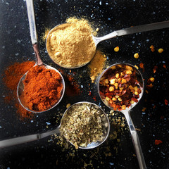 spices and herbs on silver spoons. chilli pepper, ginger, paprika, italian herbs. Kitchen flat lay design