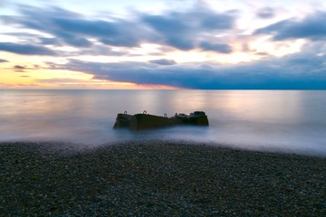 the last rays of sunset glare on the sea and pebbles