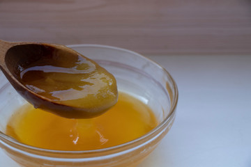 Yellow sweet honey on a white background. Flowing sweetness with a wooden spoon. Bee.