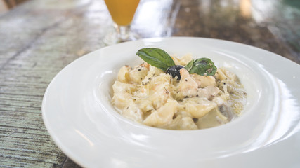 Yummy pasta on cafe table. Closeup plate with portion of tasty pasta with cream sauce placed on...