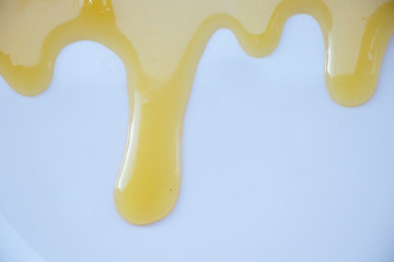 Yellow sweet honey on a white background. Flowing sweetness with a wooden spoon. Bee.