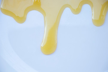 Yellow sweet honey on a white background. Flowing sweetness with a wooden spoon. Bee.