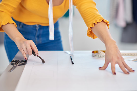Dedicated caucasian seamstress cutting seam pattern with rotary cutter.