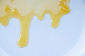 Yellow sweet honey on a white background. Flowing sweetness with a wooden spoon. Bee.