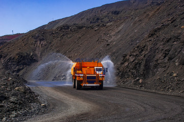 Heavy truck pours the road with water in the iron ore quarry. Dust removal, protection of the environment. Irrigation of the road from dust. The World’s Largest Sprinkler Truck © Yevhen