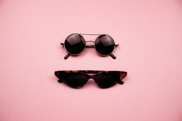 Two pairs of sunglasses flat lay on colorful pink background. Trendy round and cat eye sunglasses. Summer, holidays and vacation concept. Design for web, social media, advertising. Stock photo.