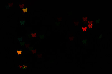 Bokeh in the form of butterflies of different colors on a dark background