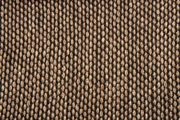 Fragment of knitted scarf of brown-black color with twisted edges. Vertical location on a white background. Close-up