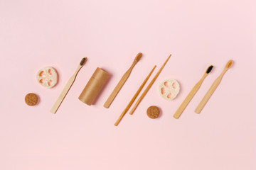 Zero waste concept. Natural bamboo toothbrush, craft tube, wooden sushi sticks, natural sponge on pink background. Flat lay, top view, copy space.
