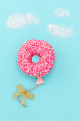 Creative food minimalism. Donut on blue background, donut in a shape of balloon in the sky, top view