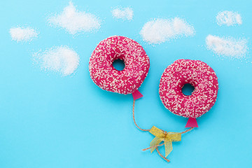 Creative food minimalism. Donut on blue background, donut in a shape of balloon in the sky, top view