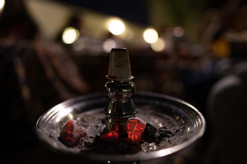 Shisha (Hookah) head with charcoal on top - Blurred people in the background