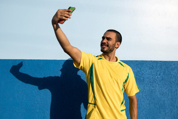 Young man, taking a selfie wearing the Brazilian football team colours