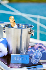 Fototapeta na wymiar Romantic luxury evening on cruise yacht with champagne setting. Empty glasses and bottle with champagne and tropical sunset with sea background