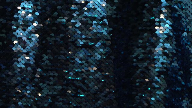 Loopable blue sequined fabric background with blinking gold lights