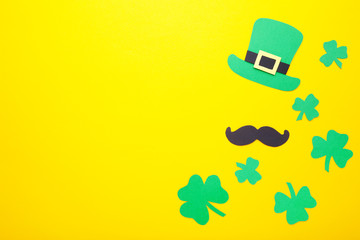 Happy Saint Patrick's of handmade paper clover leaves and hat on yellow background.