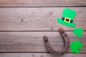 Happy Saint Patrick's of handmade paper clover leaves, horseshoe and hat on grey wooden background.