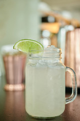 Lemonade drink in a mason jar on a bar counter and copper shakers on the background shallow depth of field