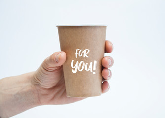 Disposable paper cup in hand on a white background. Glass inscription for you