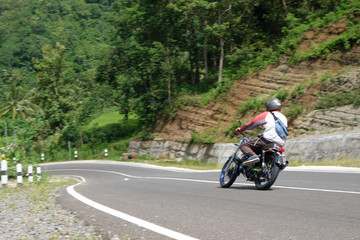 Obraz premium Mężczyzna jedzie na klasycznym motocyklu na autostradzie w górach
