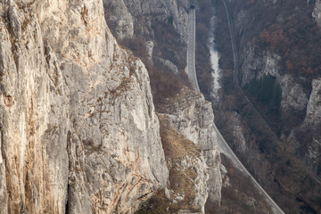 Amazing high angle view of narrow gorge and canyon with sunlit, steep, rocky cliffs raising above river, road and railroad