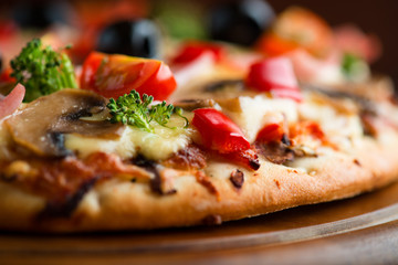 Healthy pizza with ham, broccoli, cherry tomatoes, red pepper and champignon mushrooms. Close up.