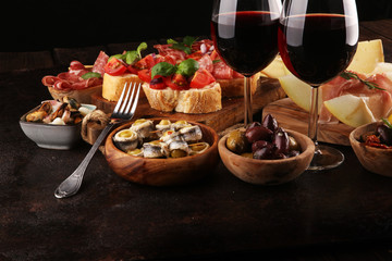 Italian antipasti wine snacks set. Cheese variety, Mediterranean olives, seafood salad, Prosciutto di Parma, tomatoes, anchovy and wine in glasses