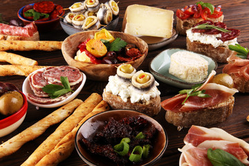 Appetizers table with italian antipasti snacks and wine in glasses. Brushetta or authentic traditional spanish tapas set, cheese variety