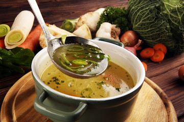 Broth with carrots, onions various fresh vegetables in a pot - colorful fresh clear spring soup....