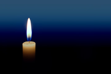 Close up of burning candle with bright yellow and blue flame against a blue gradient background