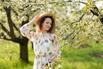 A gorgeous girl walks in a flowering spring garden. The concept of unity of man with nature