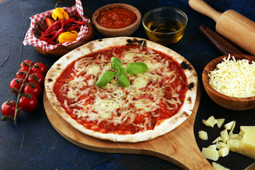 Pizza with tomatoes, mozzarella cheese, basil. Delicious italian pizza on wooden pizza board.