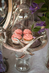 A sweet table with desserts and sweets in purple colors. Cupcakes with pink cream on a glass stand. Wedding celebration.