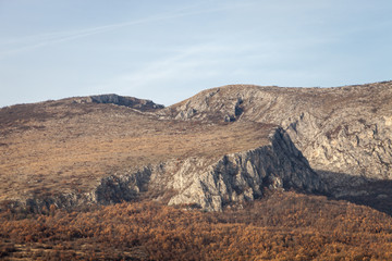 Rocky peaks and vivid autumn colors of the forest on Svrljig (Svrljiske) mountains in Serbia under a clear blue sky