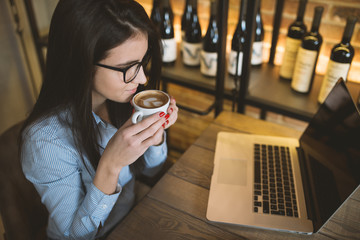 Young beautiful woman drinking coffee at cafe bar.