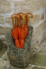 Orange umbrellas in an ancient stone stand