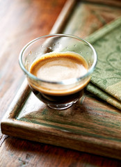 Coffee in glass cup on rustic wooden background. Close up.