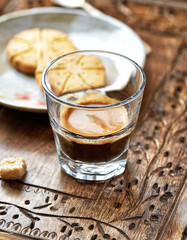 Coffee in glass cup on rustic wooden background. Close up.