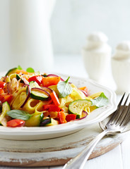 Italian pasta with red pepper, zucchini and fresh basil. Concept for a tasty and healthy meal. Bright background. 