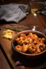 Argentinian garlic shrimp with glass of white wine on wooden table