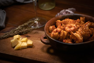 Argentinian garlic shrimp with glass of white wine on wooden table