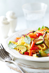 Italian pasta with red pepper, zucchini and fresh basil. Concept for a tasty and healthy meal. Bright background.