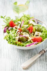 Salad with Green Olives, Tomatoes, Endive, Cucumber and Feta Cheese. Wooden background.