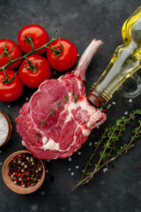 raw beef steak, beef tomahawk with spices, thyme on a stone background.