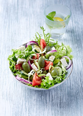 Salad with Green Olives, Tomatoes, Endive, Cucumber and Feta Cheese. Wooden background.