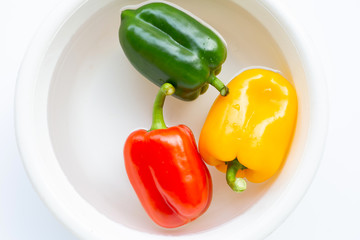 Bell pepper soaked in water. Washing fresh vegetables on white